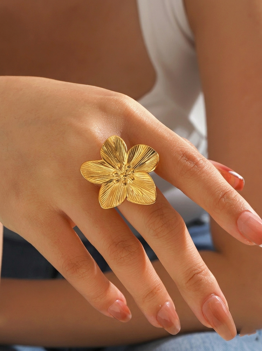 Close-up view of a hand wearing the Hibiscus Molten Adjustable Ring showcasing the oversized matte gold hibiscus motif