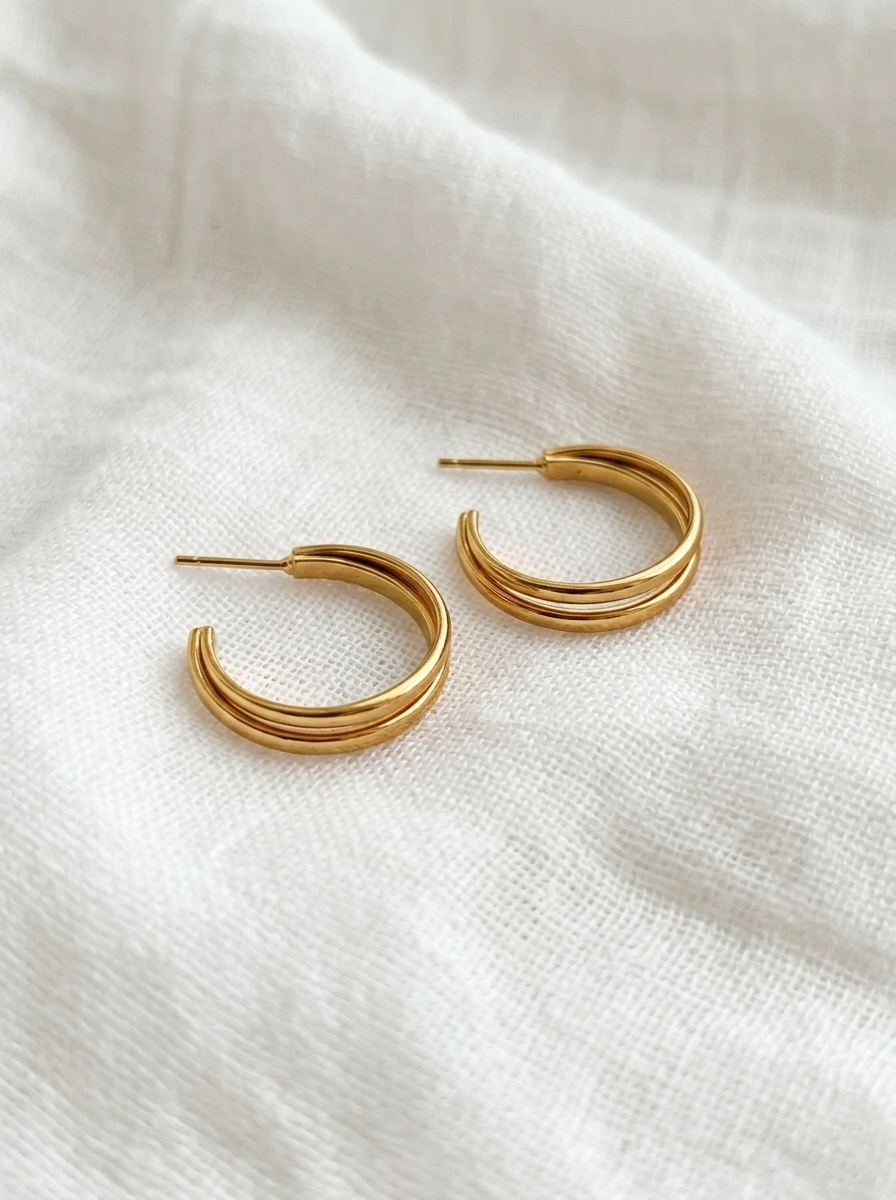 Pair of polished gold Serena Grand Double Hoops featuring a twin-band open hoop design with post backs on soft textured white linen